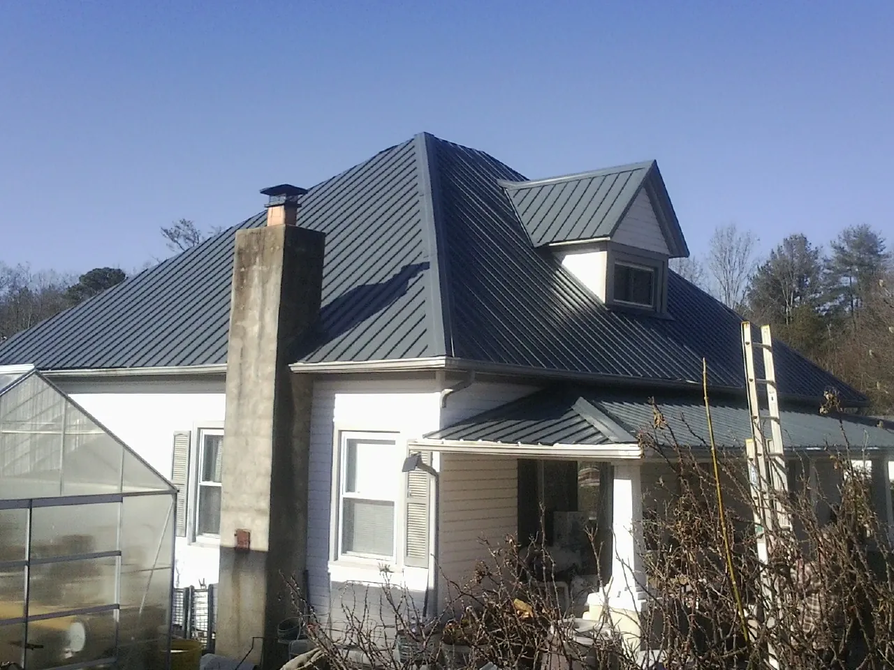 Dark blue standing seam metal roof on a white farmhouse with dormer — Slate & Tile Roof Repair by Roofing Brothers in La Honda