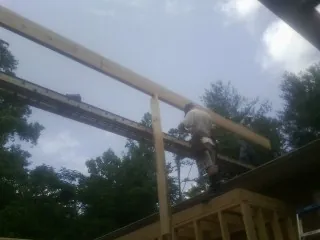 Carpenter setting a ridge beam over a new addition frame — Ice Dam Removal by Roofing Brothers in La Honda