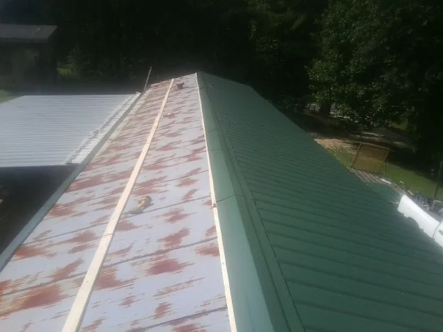 Old rusted panels beside newly installed green metal roofing — Wind Damage Roof Repair by Roofing Brothers in La Honda