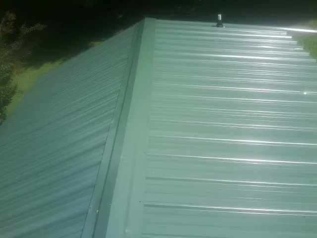 New green metal panels meeting at the ridge of a roof — Flat Roof Repair work by our crew in La Honda
