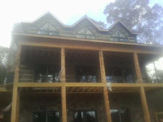 Dormers and porch framing on a large log home under construction — Roof Coating work by our crew in La Honda