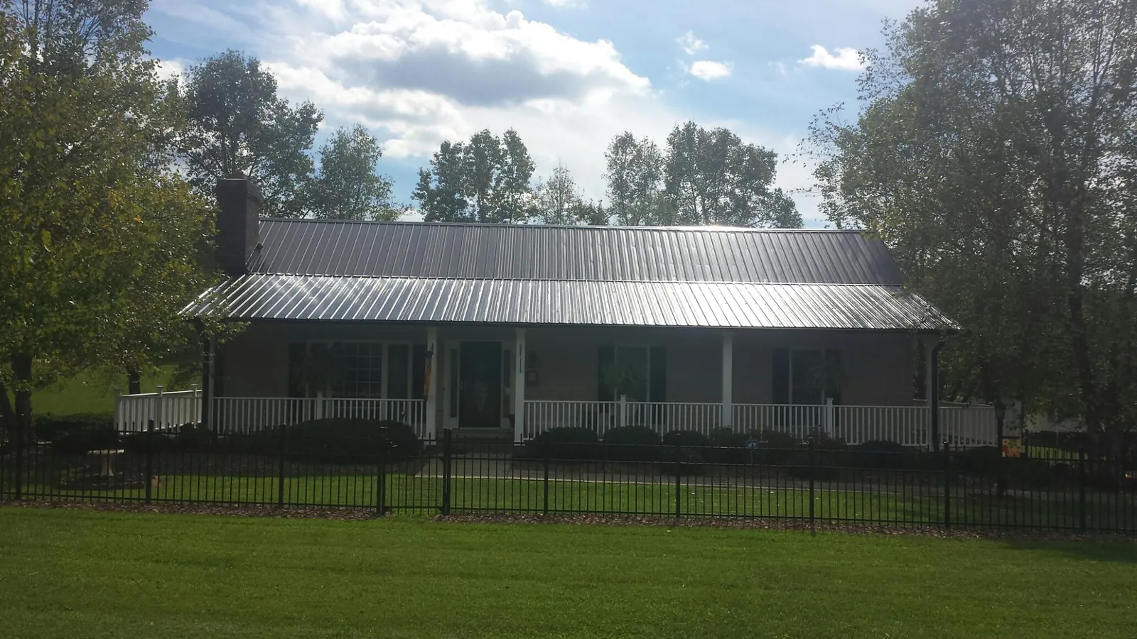 Gray metal roof on a brick ranch with a full width front porch — Gutter Guard Installation work by our crew in La Honda