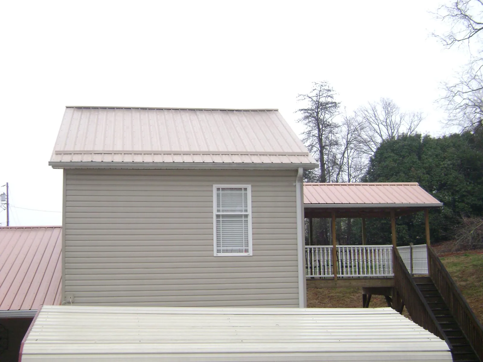 Tan metal roofs on a two story addition and attached porch, from a Roof Replacement job in La Honda