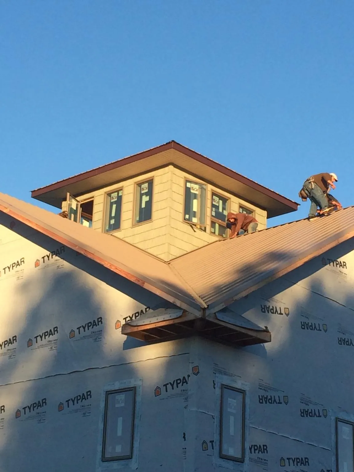 Roofers working around a rooftop cupola on a new metal roof at sunset — Roof Waterproofing in La Honda by Roofing Brothers